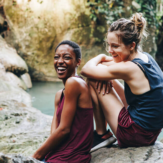 Two women sitting next to a natural spring after a long hike.