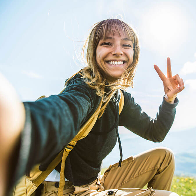 A woman in hiking clothes taking a selfie.